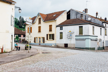 Une ancienne rue pavée dans un village français. Un carrefour de rues dans un vieux village de France. Un homme assis dans un carrefour.