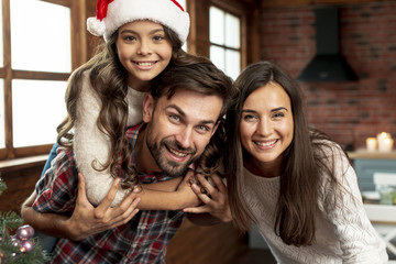 Medium shot happy parents and girl posing indoors