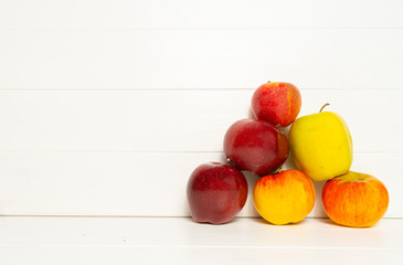 Fototapeta na wymiar Red and yellow apples on a white wooden background. Harvest composition. Background with space for text.