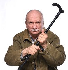 Old angry man threatening with a cane in studio