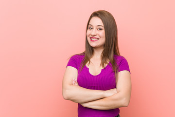 Fototapeta premium Young hispanic woman against a pink wall smiling confident with crossed arms.