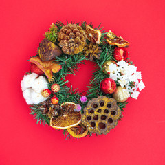 Beautiful Decorative Christmas wreath on red background. Top view, flat lay style.