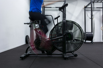 Motion blur concept of female fitness trainer performing on attack bicycle.