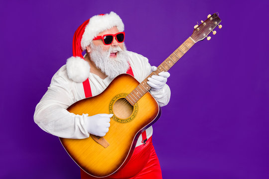 Portrait of his he nice funny cool cheerful bearded Santa playing guitar having fun midnight entertainment isolated over bright vivid shine vibrant violet lilac background