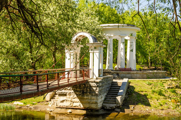 A bridge in the park leading to the white gazebo.