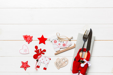 Top view of New Year dinner on wooden background. Festive cutlery on napkin with christmas decorations and toys. Family holiday concept with copy space
