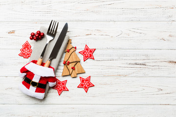 Fototapeta na wymiar Top view of fork and knife tied up with ribbon on napkin on wooden background. Christmas decorations and New Year tree. Happy holiday concept with empty space for your design