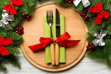 Holiday composition of plate and flatware decorated with fir tree on wooden background. Top view of Christmas decorations. Festive time concept