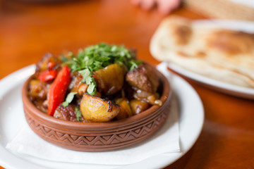 Roasted meat with potatoes, ojaxuri, hot in Georgian on a wooden table. Georgian cuisine