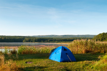 tent on the shore of a beautiful lake against a background of blue sky