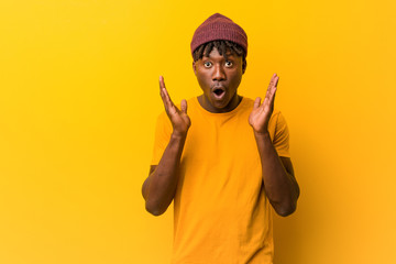 Young black man wearing rastas over yellow background surprised and shocked.