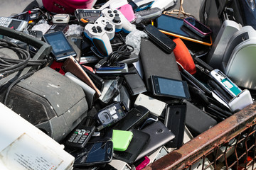 Close up on pile broken cell phones and electronic devices at an electonic waste centre