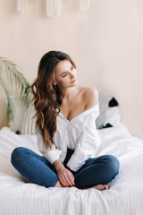 Obraz premium Portrait of a young beautiful woman in bed in the morning at home. Beautiful brunette in the bedroom. Good morning. Lifestyle.