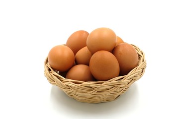 Many eggs in a wooden basket on white background