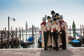 A group of people in masks for the Venice carnival in San Marco piazza, in the background the island of San Giorgio Maggiore. Italy