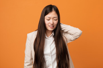 Young business chinese woman suffering neck pain due to sedentary lifestyle.