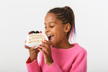 Image of happy african american girl holding and eating piece of torte
