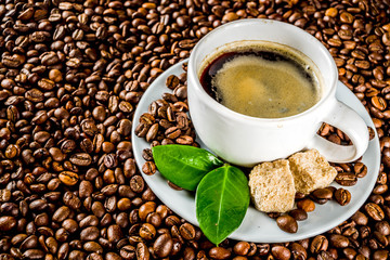 Cup of espresso with coffee beans. ground coffee and leaves on rustic background