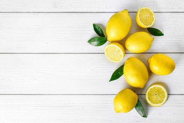 Fresh juicy lemons on white rustic table. Top view lemon background and leaves.