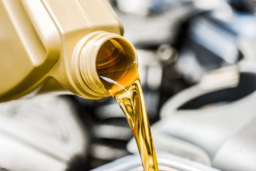 Motor oil poring. Car maintenance change and refuel yellow liquids.