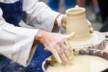 Man hands making ceramics ware. Modeling earthenwaredetail on potter's wheel. Creating vase or jar from white clay close-up.