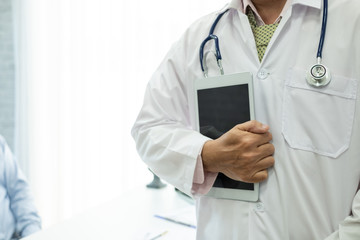 Close-up. Doctor man standing holding tablet at office.