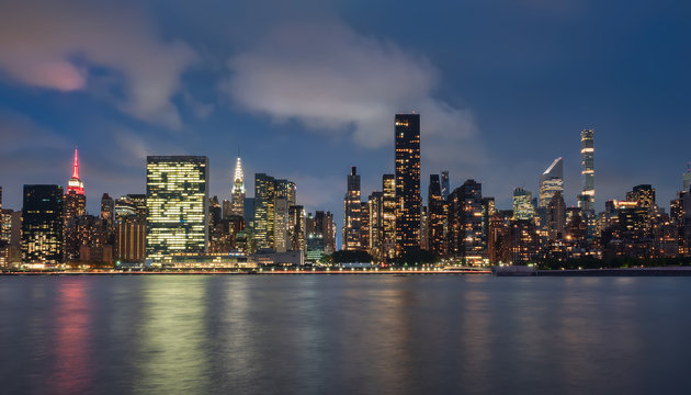 vista del skyline de Manhattan , Nueva York,USA,por la noche, desde la zona de Dumbo. Fotografia de larga exposicion, con reflejos en el agua con textura seda