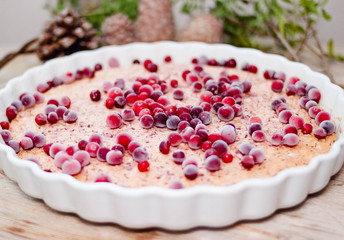 Cake or baked pudding of cottage cheese with red bilberry on white baking dish on wooden background
