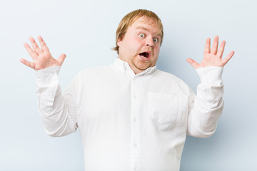 Young authentic redhead fat man celebrating a victory or success, he is surprised and shocked.