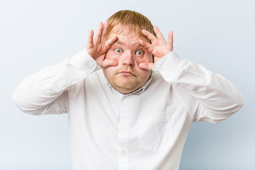 Young authentic redhead fat man keeping eyes opened to find a success opportunity.