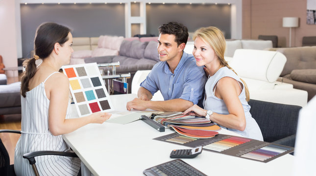 Young family consulting with seler about  sofa color