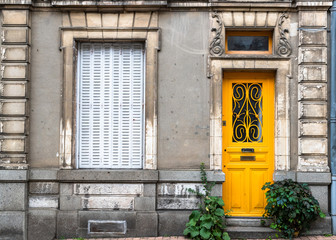 Fototapeta na wymiar Facade view of an old traditional french house design with closed window shutters and Yellow door, vintage french style
