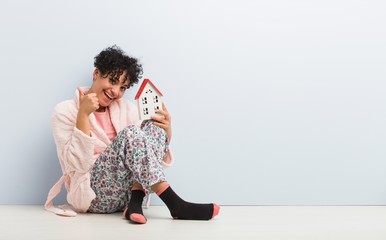 Young african american woman sitting holding a house icon