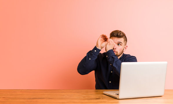 Young Man Working With His Laptop Looking Far Away Keeping Him Hand On Forehead.