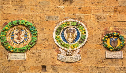 Fototapeta na wymiar Ancient coats of arms depicted on majolica on wall of medieval town hall