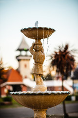 Imagen en primer plano de una fuente con el agua cayendo en un parque al atardecer 