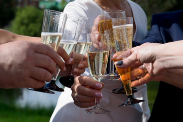 Joining hands with glasses of poured wine. The celebratory clinking of champagne at a gala reception.