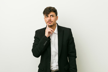 Young business hispanic man looking sideways with doubtful and skeptical expression.