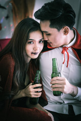 Happy couple of love in Halloween costume and makeup celebrating and drinking beer in Halloween night party