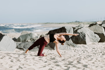 Young Woman Practicing Yoga On The Beach By The Ocean, Yoga Poses Set Against Beautiful Background