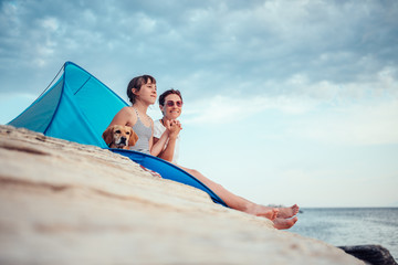 Fototapeta premium Mother and daughter sitting in beach tent by the sea and holding hands