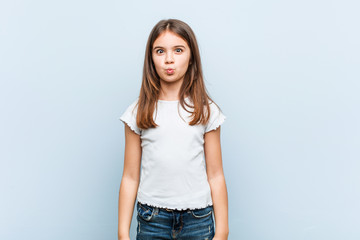 Fototapeta premium Cute girl blows cheeks, has tired expression. Facial expression concept.