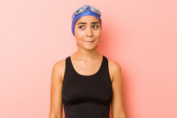Young arab swimmer woman isolated confused, feels doubtful and unsure.