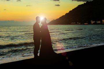 Silhouette wedding bride and groom on beach sunshine In the evening