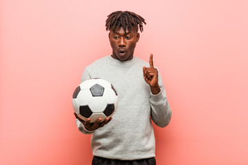 Young fitness black man holding a soccer ball having some great idea, concept of creativity.