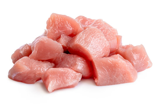 A pile of cut up uncooked boned chicken breast isolated on white.