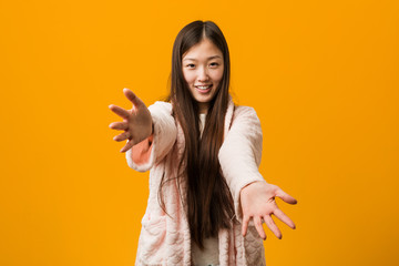 Young chinese woman in pajama feels confident giving a hug to the camera.