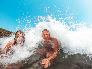 Father and daughter getting splashed by the sea wave