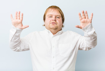 Fototapeta premium Young authentic redhead fat man showing number ten with hands.
