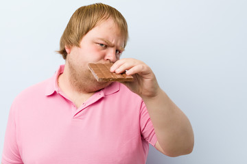 Caucasian crazy blond fat man holding a chocolate tablet